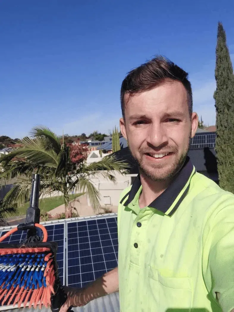 Mike Marrable from Mike's Window, Gutter, and Solar Cleaning, standing outdoors with solar panels and a palm tree in the background, showcasing professional cleaning equipment in Mildura, Sunraysia region.