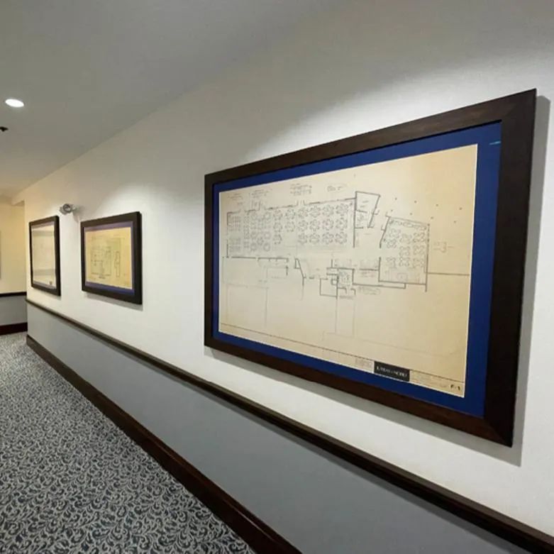 Framed architectural drawings installed in a multi-piece wall display along a corridor