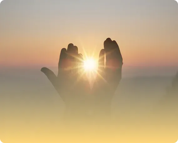 Hands in prayer framing the sunrise at dawn, symbolizing hope, healing, and positive energy in nature—spirituality and wellness.