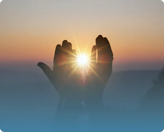 Hands in prayer framing the sunrise at dawn, symbolizing hope, healing, and positive energy in nature—spirituality and wellness.