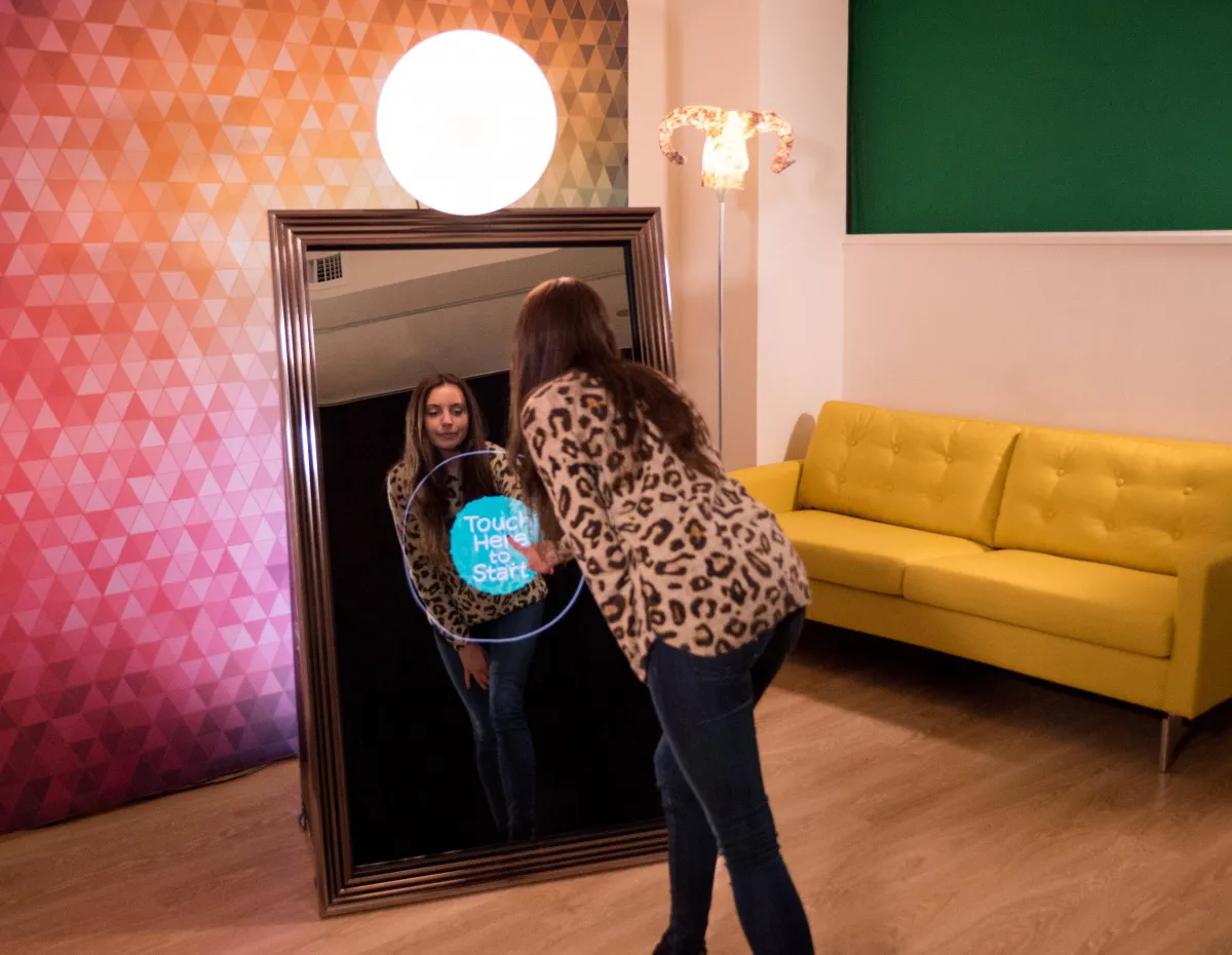 Guest using an interactive mirror photo booth in a colorful lounge setting
