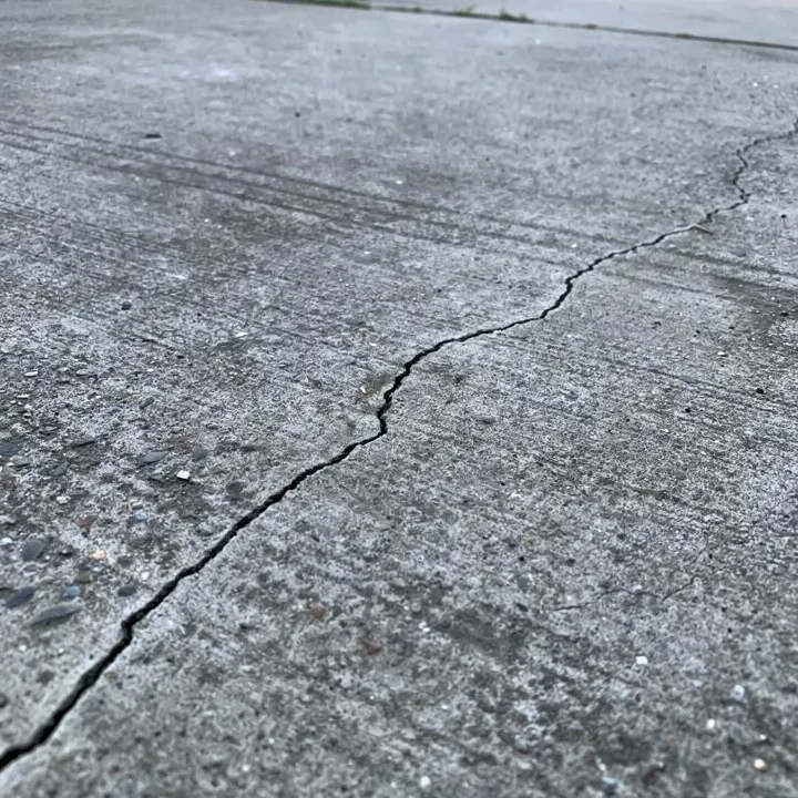 Close-up of a hairline crack on an aging concrete driveway surface in Beloit, Wisconsin.