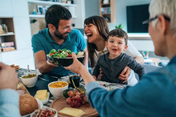 Happy family enjoying a meal together at the dining table, sharing food and smiling.