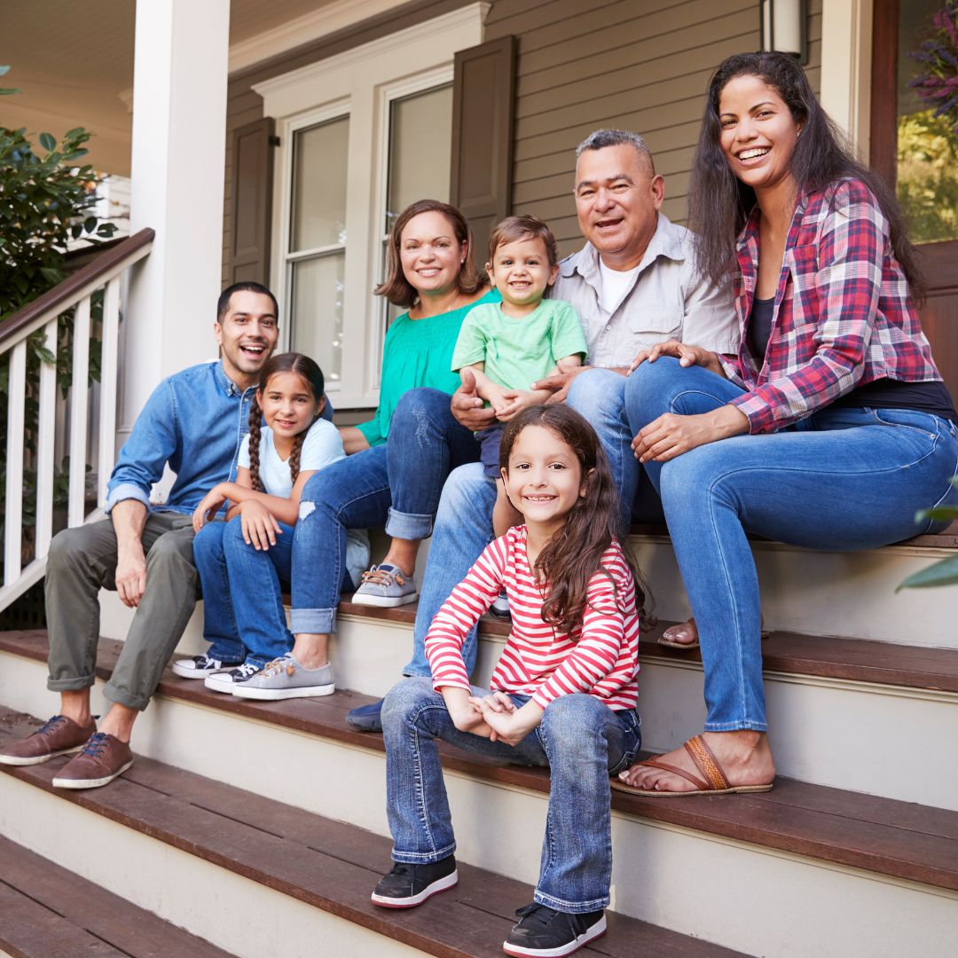 Parents, kids and grandparents sitting casually on front porch step.
