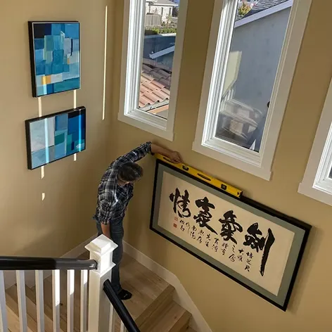 Residential gallery wall installation above a modern living room sofa with professionally balanced artwork placement
