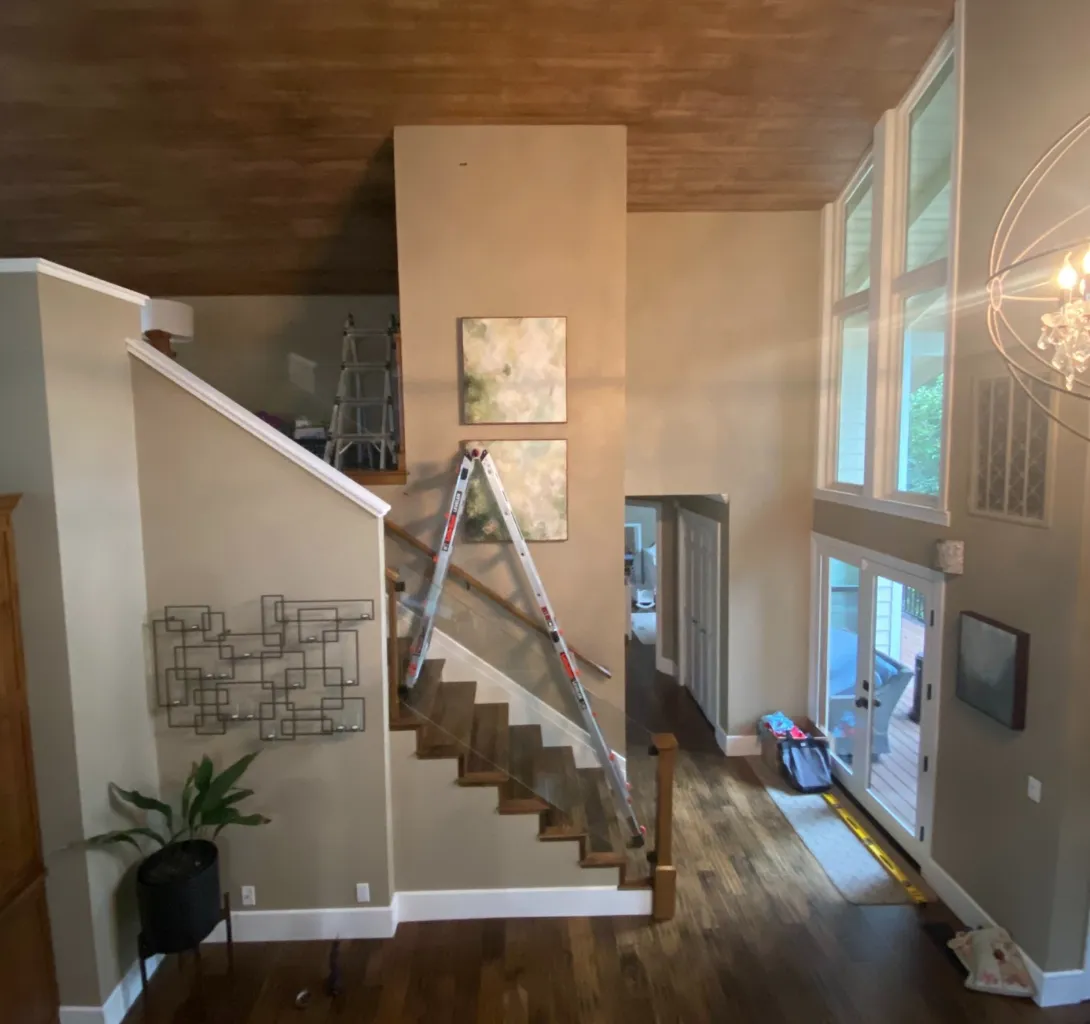 residential artwork installation and picture hanging in a high stairwell using a ladder