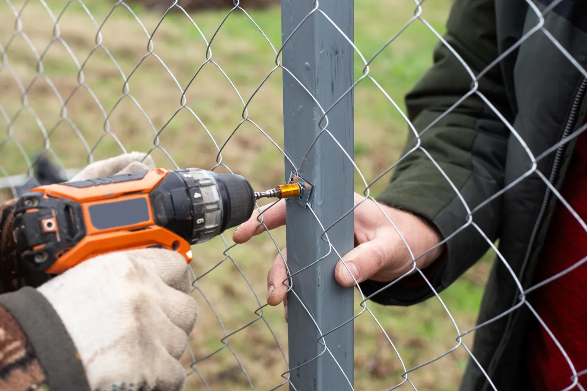 man in gray hoodie standing beside chain link fence