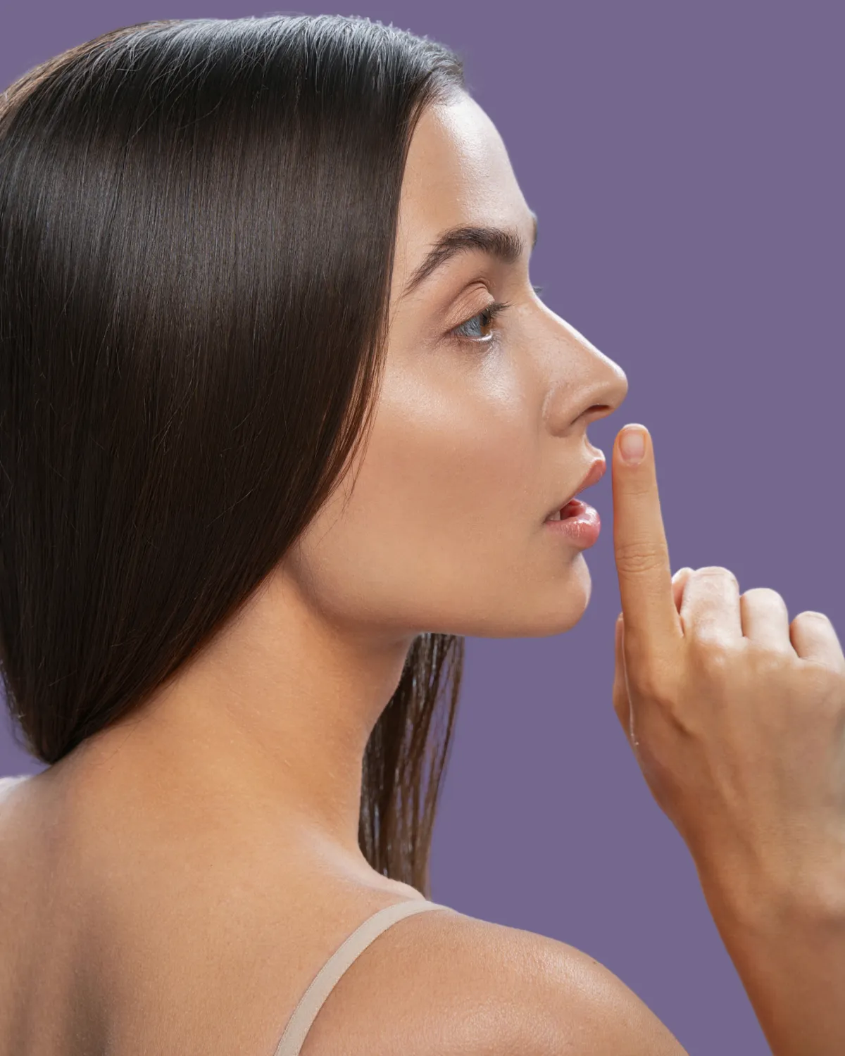 Woman touching her nose, showing results of facial plastic surgery rhinoplasty.
