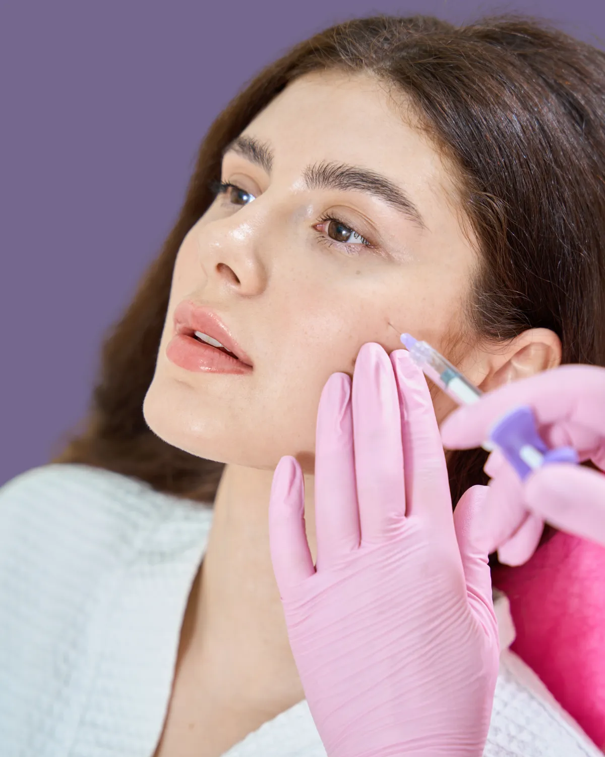 Surgeon touching woman’s cheek for facial plastic surgery.