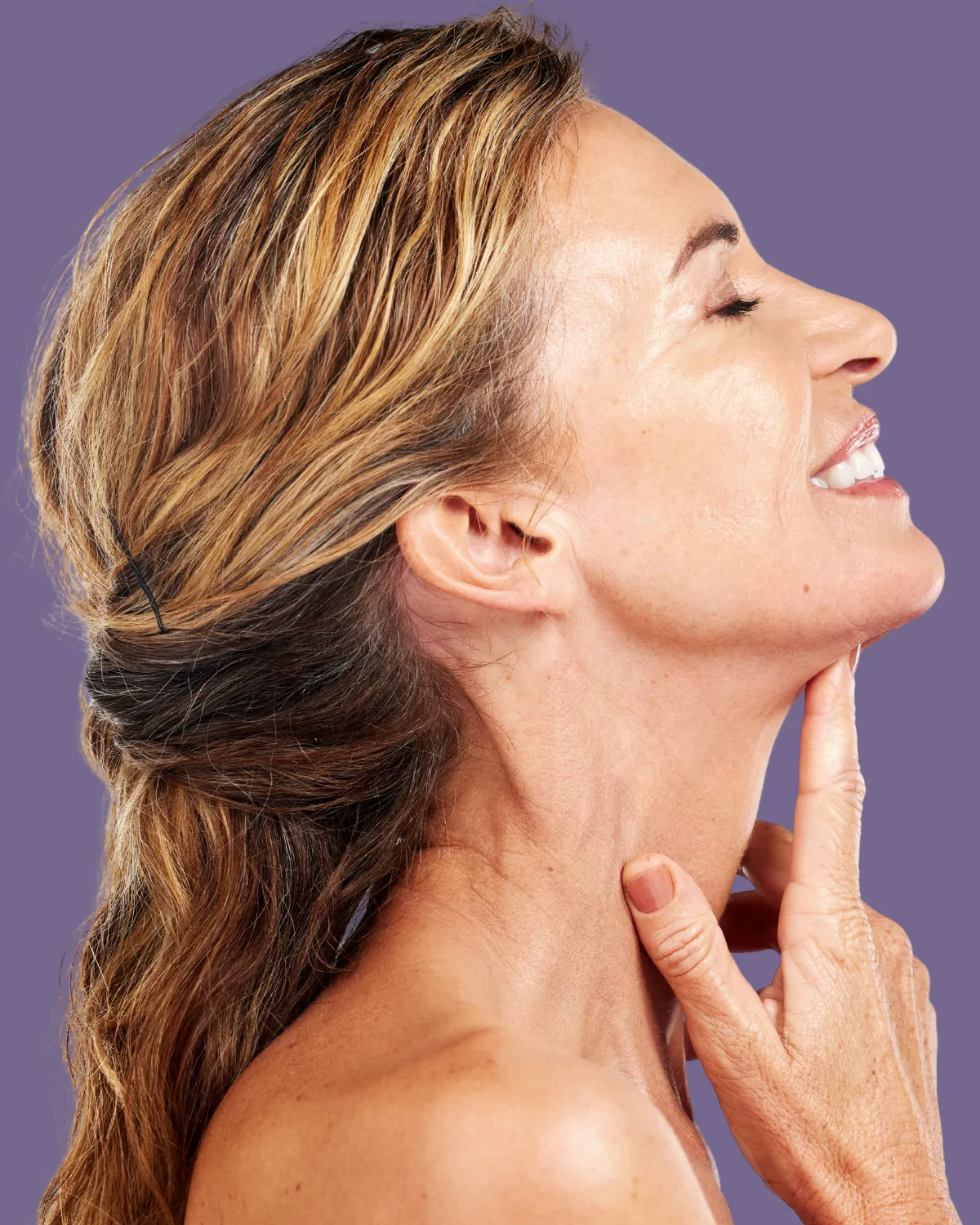 Woman touching her neck to show skin tightening after facial plastic surgery neck lift.