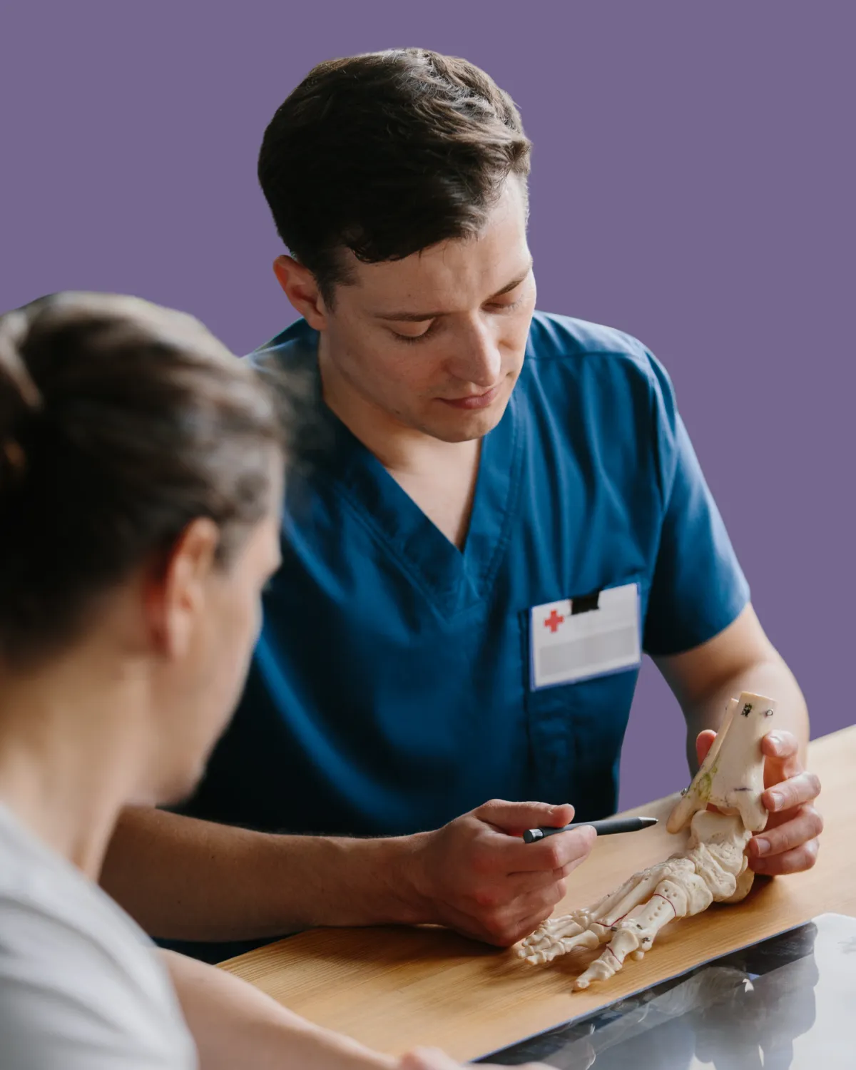 Doctor showing foot bone model to patient for orthopedic specialty surgery.