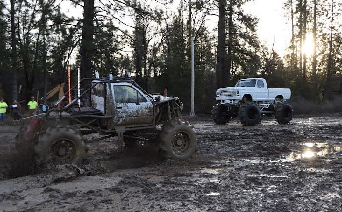 Mud truck splashing through deep mud pit at Miller Mud Boggs