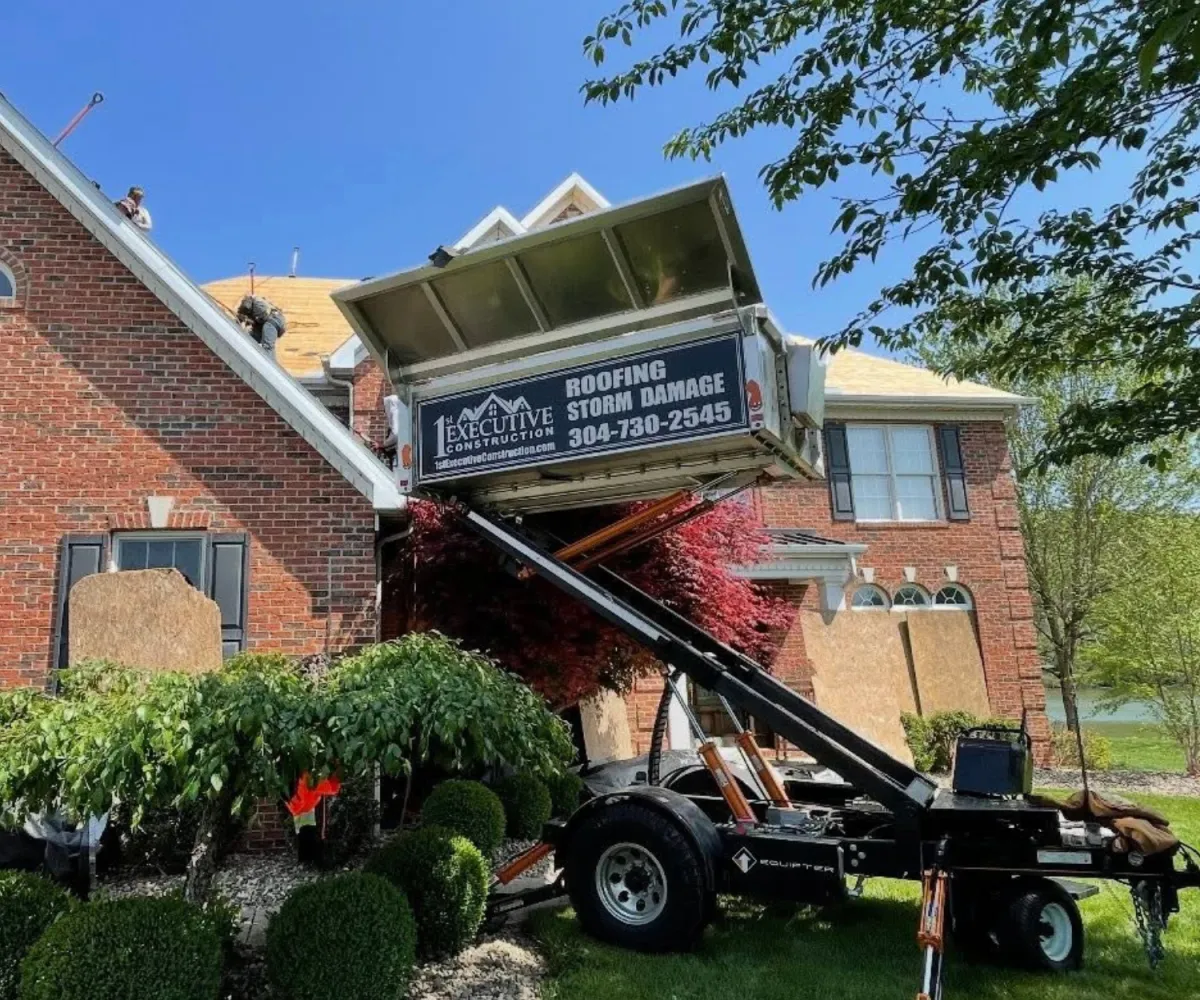 Brick two-story home with a newly installed shingle roof and a 1st Executive Construction company vehicle in the foreground.