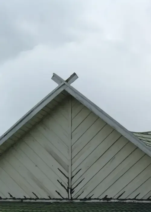 Roof edge and gable under cloudy skies showing an area prone to recurring water issues