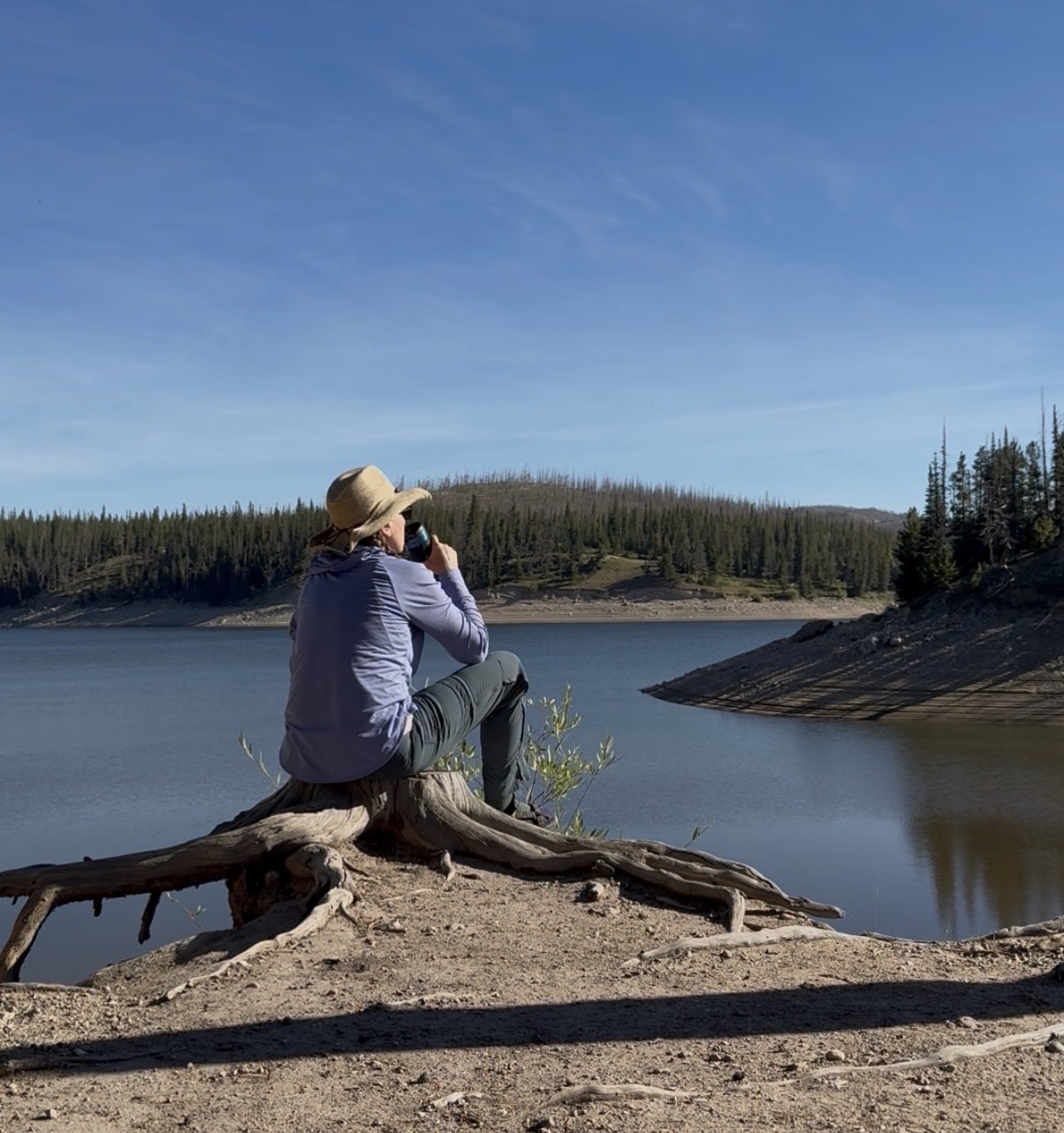 Coach Joy relaxing with a cup of coffee beside a lake