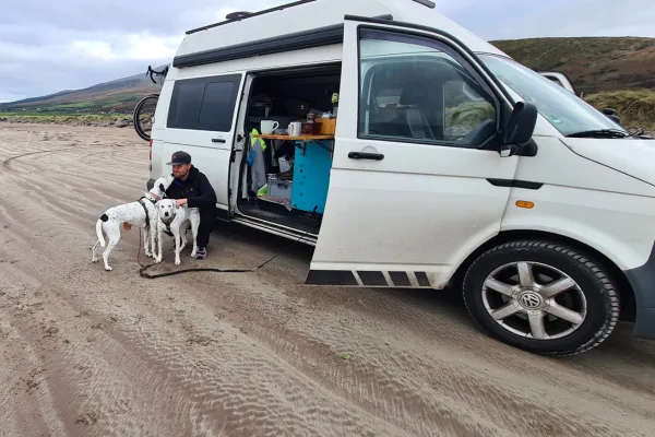 Vanlife mit Hund in Europa. Chris mit den Hunden Mia und Maya vor dem VW T5 Camper Pepe in Norwegen. Reisen, Freiheit und Abenteuer auf vier Rädern.