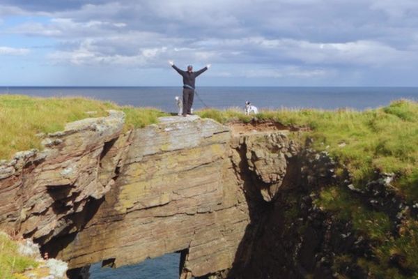 Vanlife in Schottland: Chris und Hund auf einer Klippe mit Blick auf das Meer. Roadtrip, Wandern mit Hund und Abenteuer durch die schottischen Highlands.