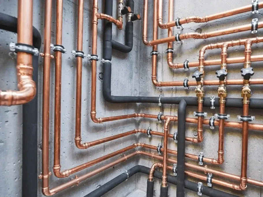 Modern emergency plumbing setup in Breckenridge, CO with copper, stainless steel pipes, valves, and fittings in a clean, organized workshop.