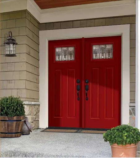 A red double steel entry door with atrictic glass inserts and black handles.