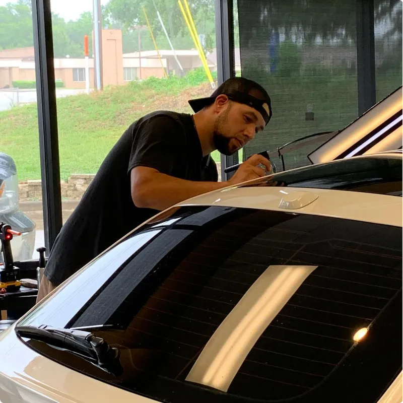 Technician repairing car dent without repainting panel