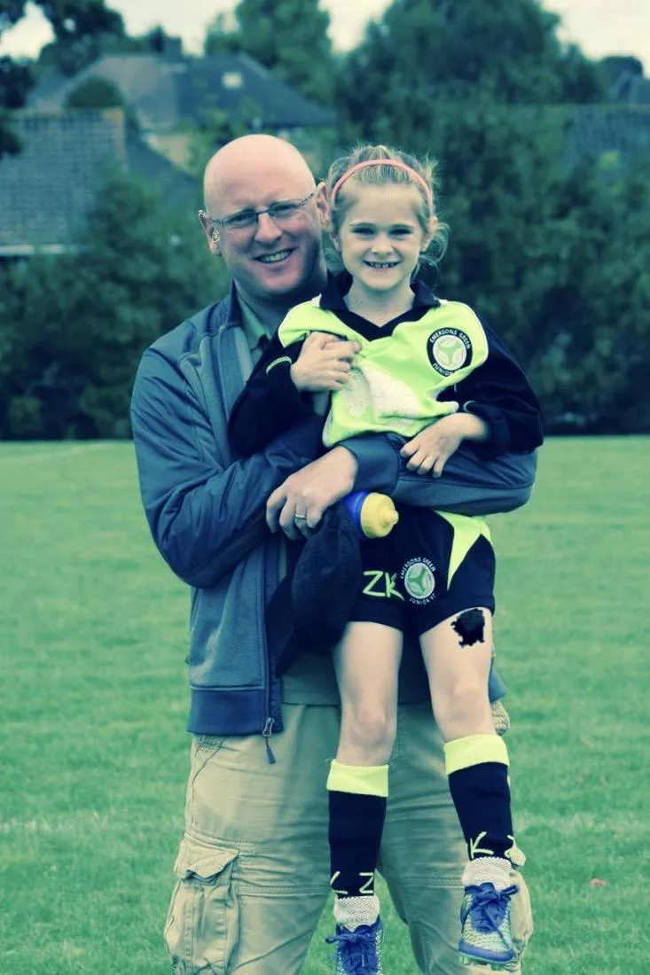 Image of Stuart Russ, Co-Chairman at Emersons Green JFC.man holding up his daughter who as been laying football 
