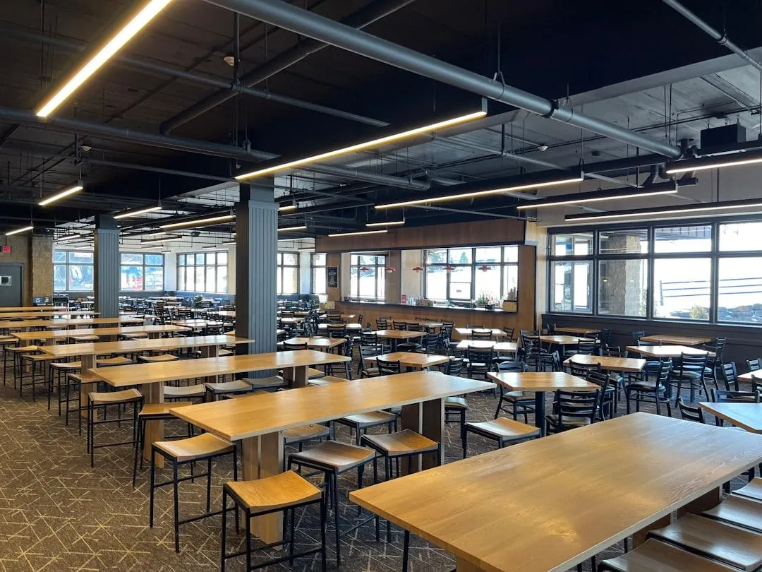 a woman in a green shirt and black gloves vacuuming a gray ottoman