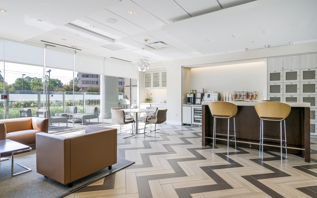 a woman in a green shirt and black gloves vacuuming a gray ottoman