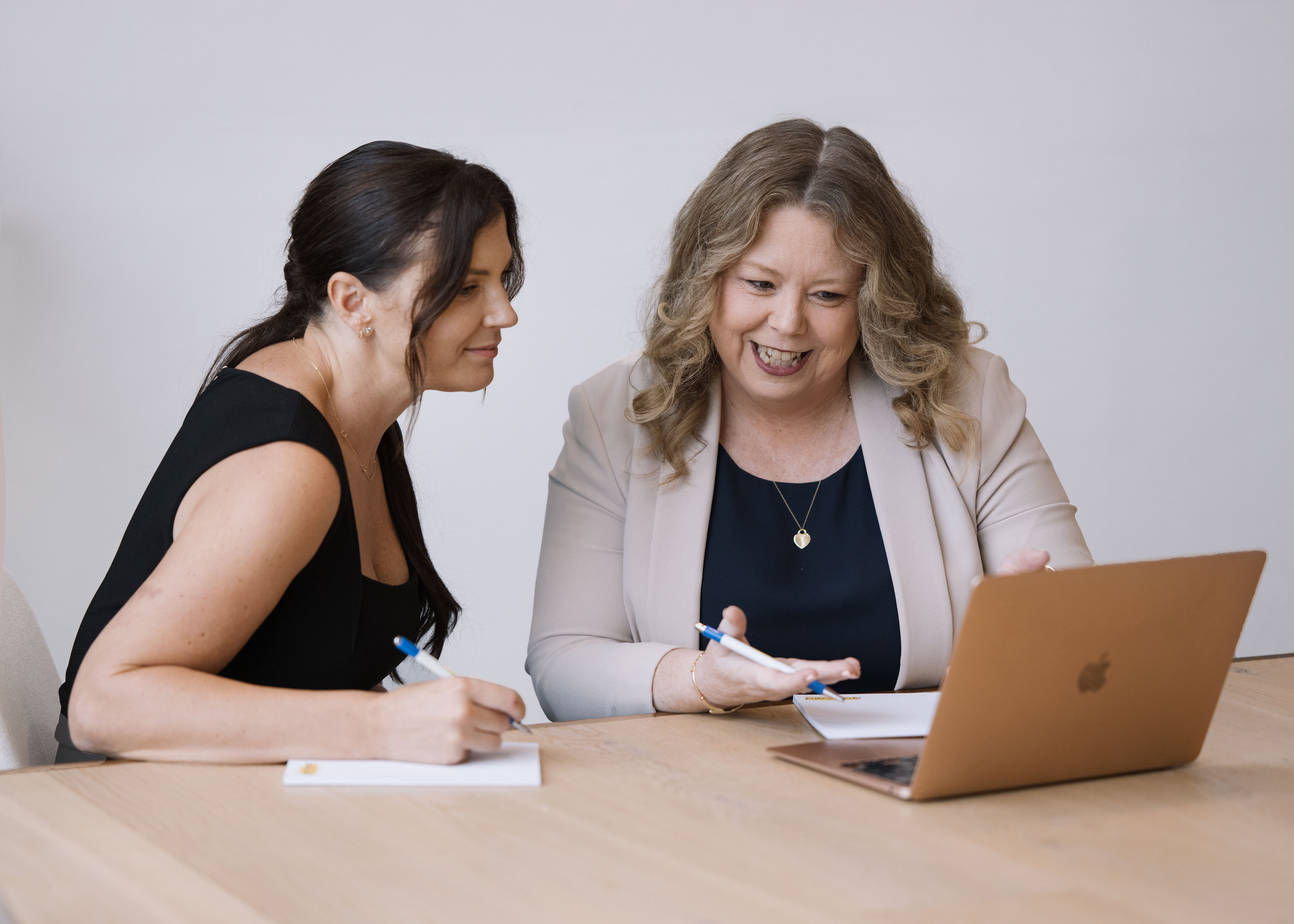 Small group of business owners in a workshop setting with the facilitator, engaged in discussion around a table.