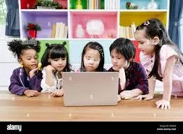 Students sit in a semicircle watching the teacher on a laptop