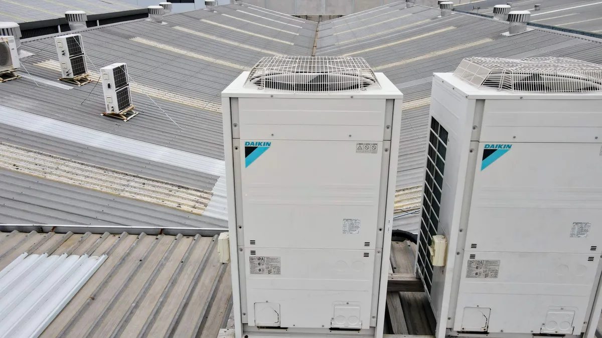 Row of large Daikin VRV outdoor compressor units installed outside a modern home