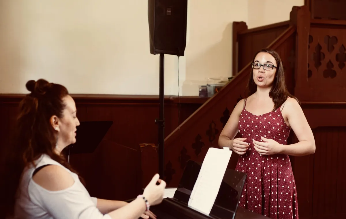 Midge playing piano while student sings