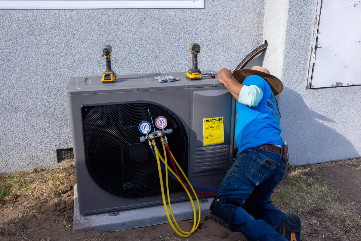 Professional HVAC technician servicing a residential outdoor AC unit in Fresno, illustrating reliable heating and cooling services by Borgens Construction Inc.