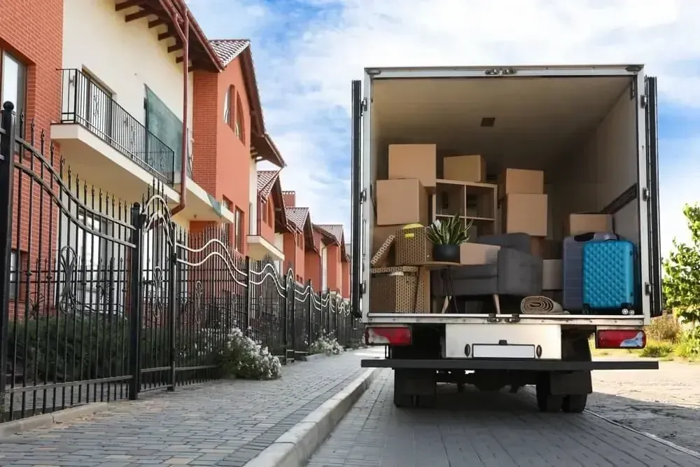 A moving truck being loaded up outside of a residential home.
