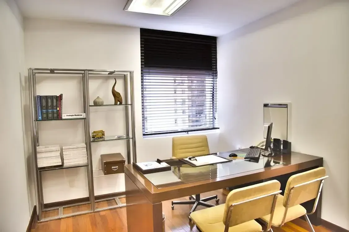 Modern office with a desk, computer, chair, shelf, and window with blinds.