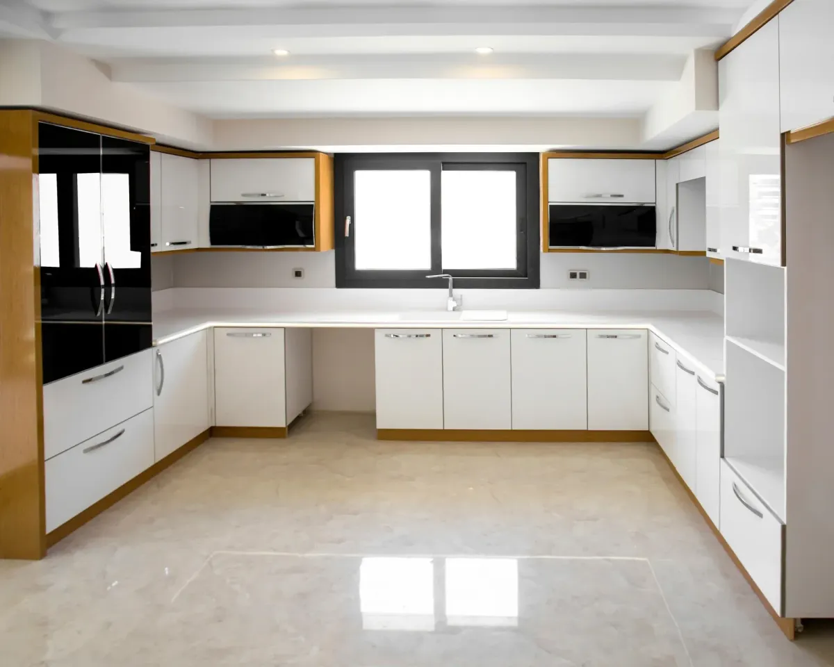 Modern kitchen interior with white cabinets, appliances, and a window letting in natural light.