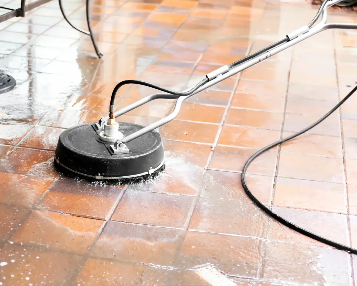 Floor scrubber machine cleaning tiled surface, with water splashes.