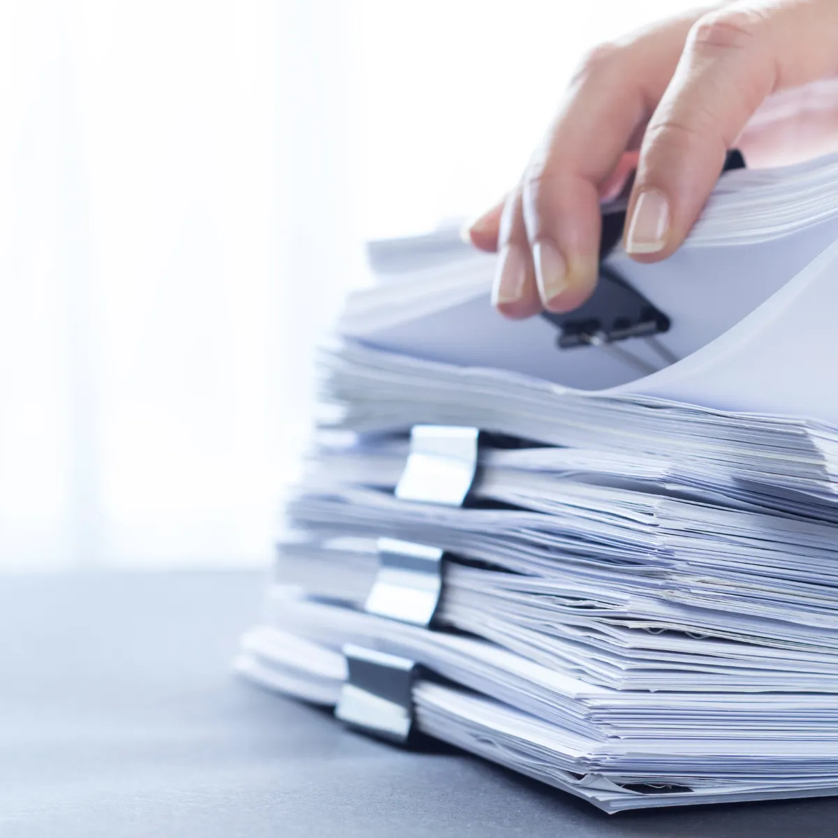 A hand is sorting through a stack of papers