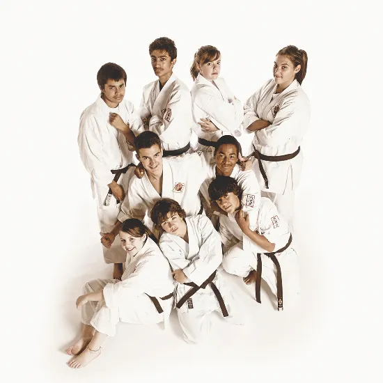 Two teenage boys in white gis practicing a block and punch technique in a dojo setting