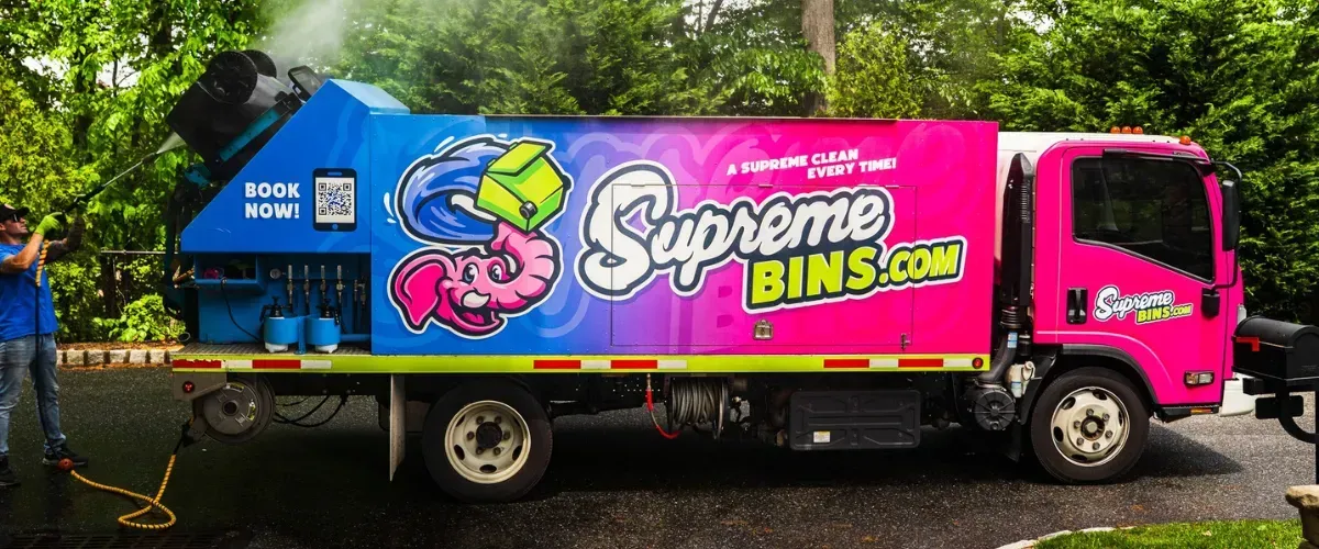 Supreme Bins technician using pressure washer on a trash bin cleaning truck