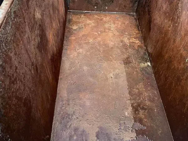 Dirty interior of a trash bin filled with old food packaging and grime