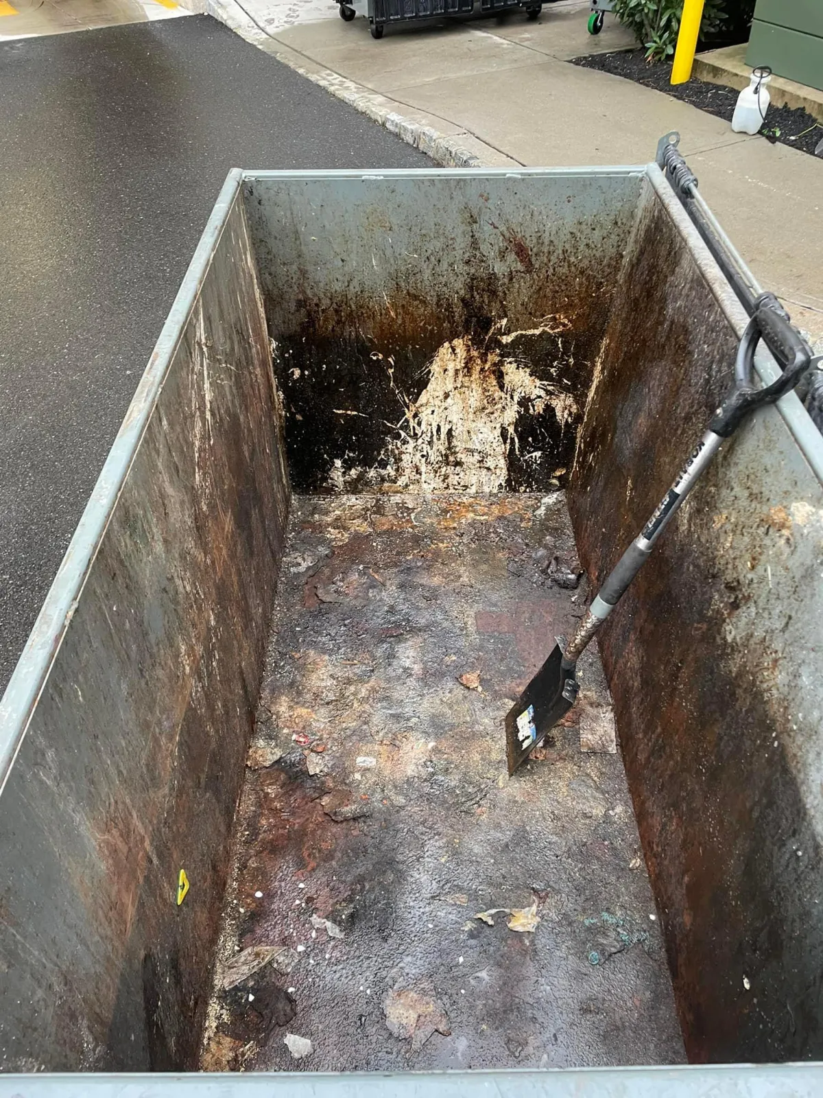 Dirty interior of a trash bin filled with old food packaging and grime