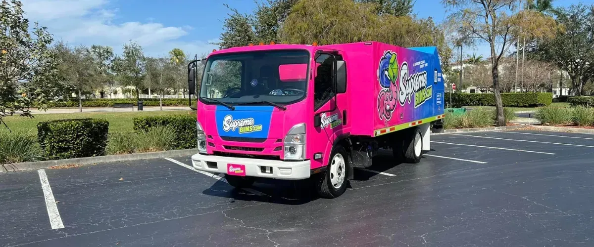 Supreme Bins pink and blue trash bin cleaning truck parked in lot