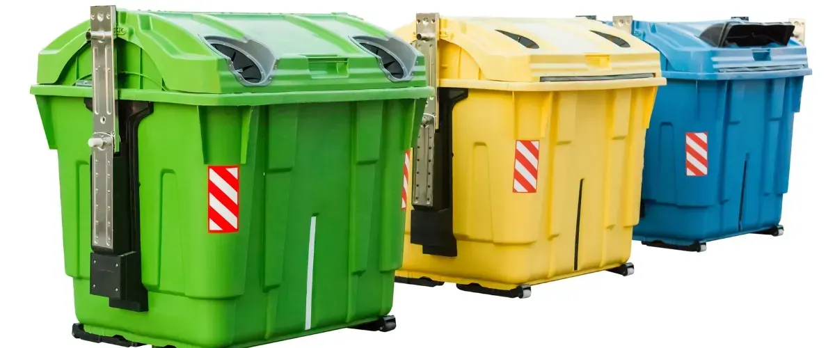 Green, yellow, and blue recycling bins lined up for waste separation and collection.