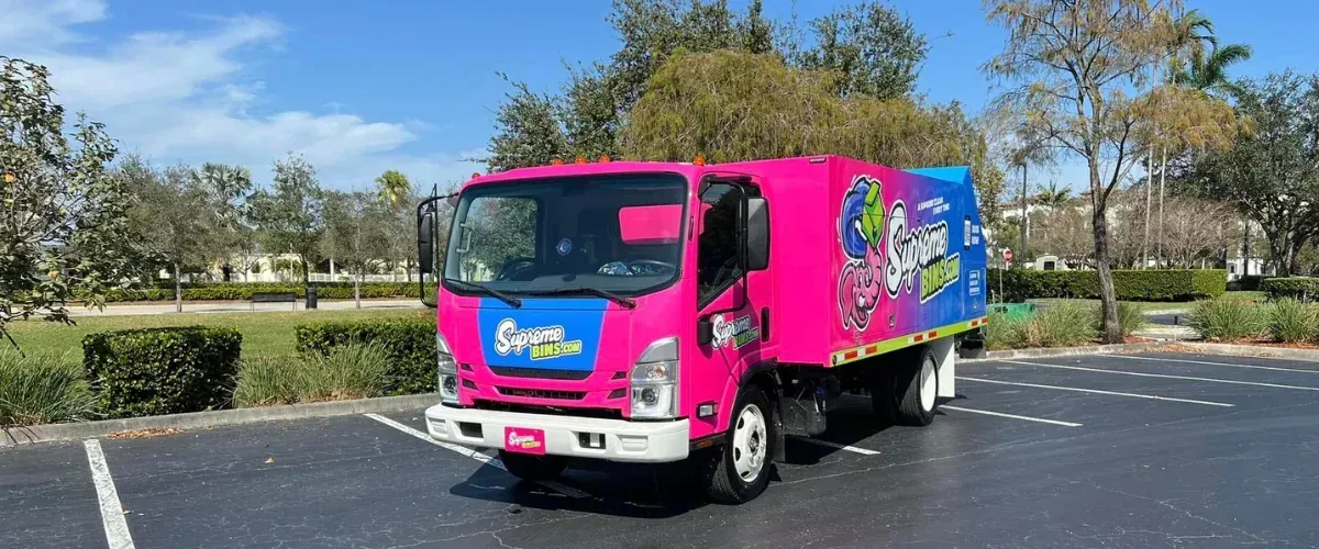 Supreme Bins pink trash bin cleaning truck parked outdoors, used for residential and commercial bin cleaning services.