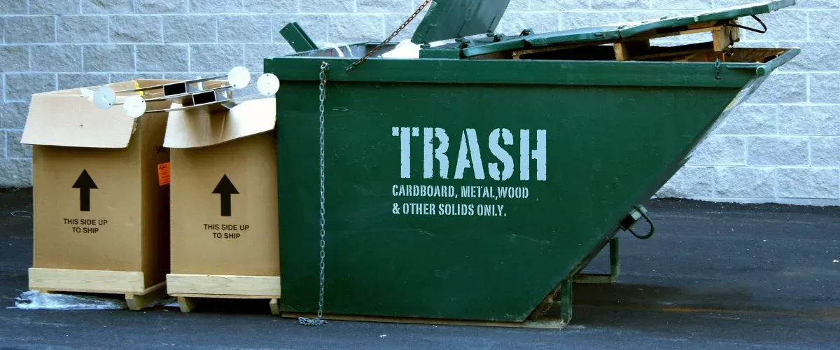 Green roll off dumpster filled with cardboard and commercial waste