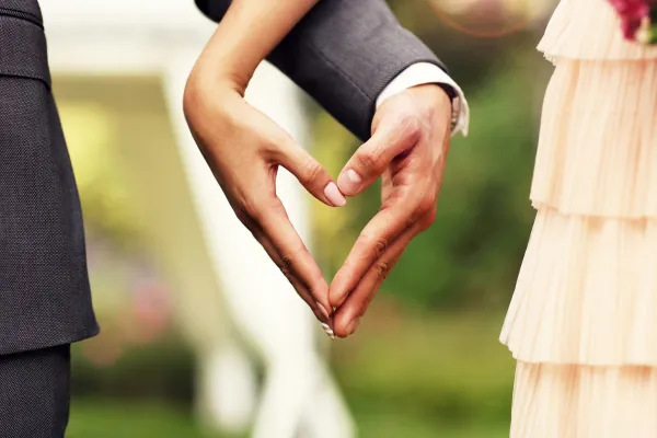 bride and groom making heart shape with hands