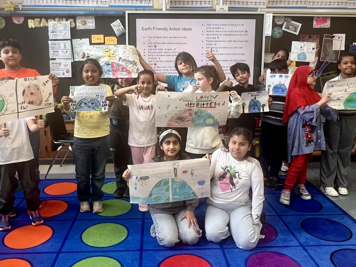 Elementary students holding up their hand-drawn Earth-friendly action posters
