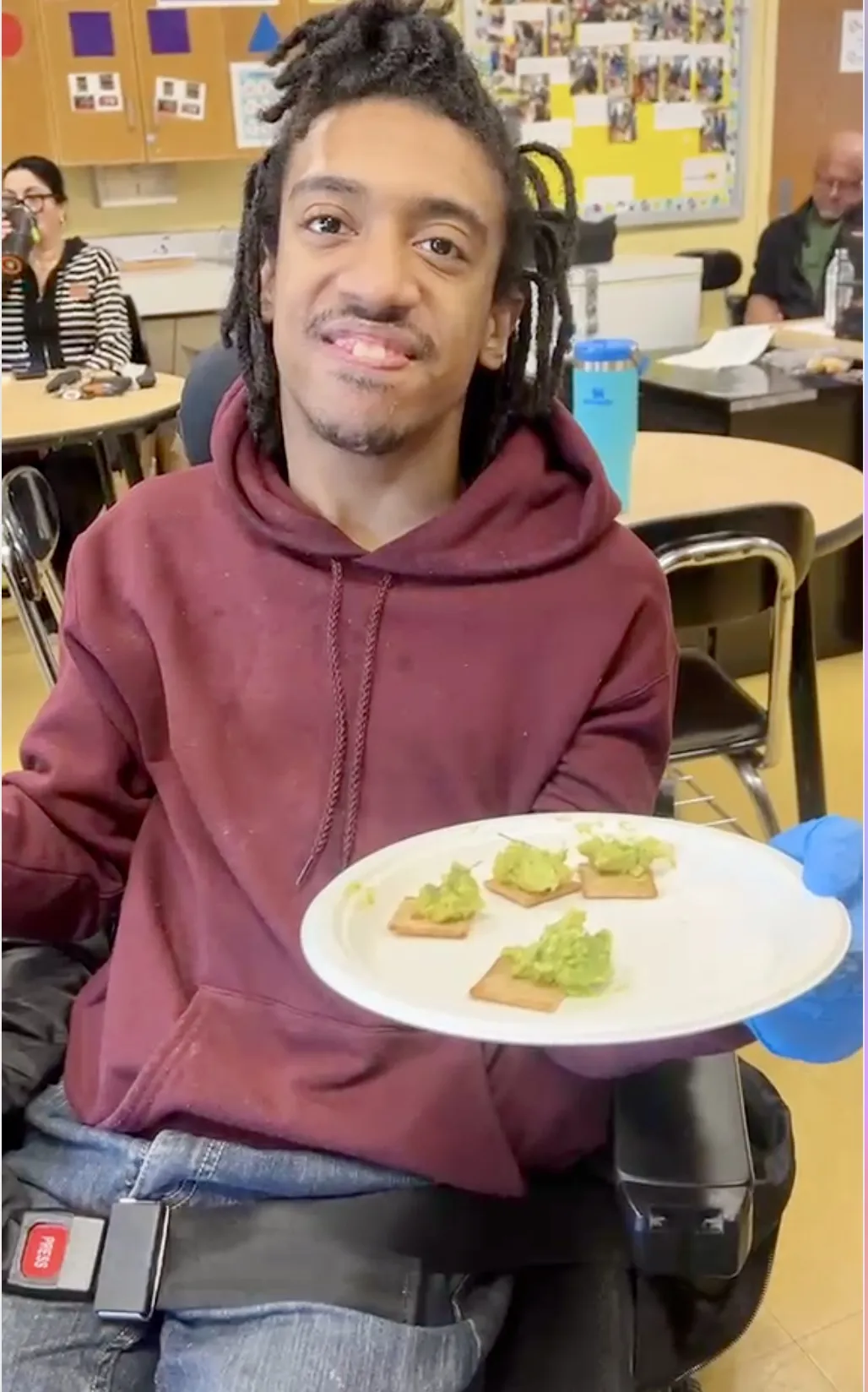 Student smiling with the guacamole crackers prepared in a cooking lesson