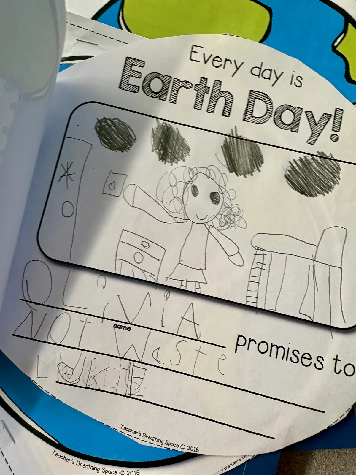 Child's Earth Day worksheet with a drawing and a handwritten promise not to waste