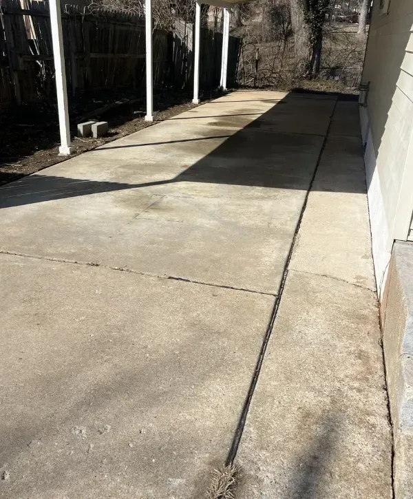 Dirty concrete driveway before pressure washing with visible stains and buildup next to a residential home in St. Charles County, MO.